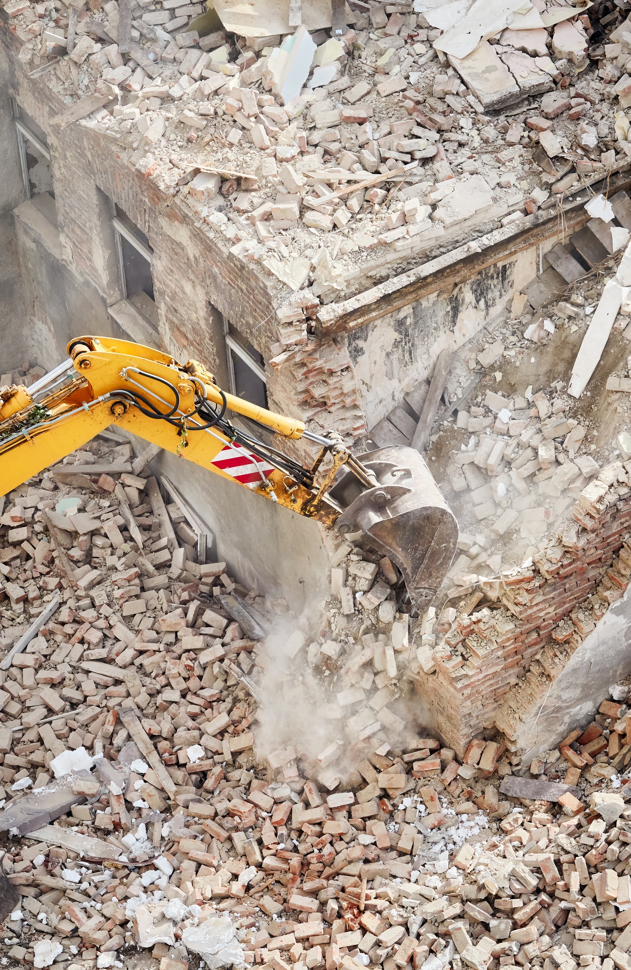 Excavator bucket in dust cloud during building demolition.